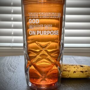 A glass with the words " god is on purpose ".